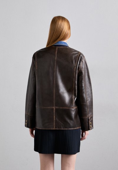 Bruine leren jas met een boxy ontwerp, gedetailleerde stiksels en gouden knopen. Bevat een contrasterende denim kraag en een gestructureerde stof.