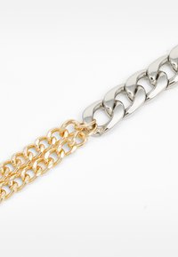Silber- und Goldkette mit ineinander verschlungenen Gliedern; glatte Textur mit polierter Oberfläche, die zwei verschiedene Metalltöne verbindet.