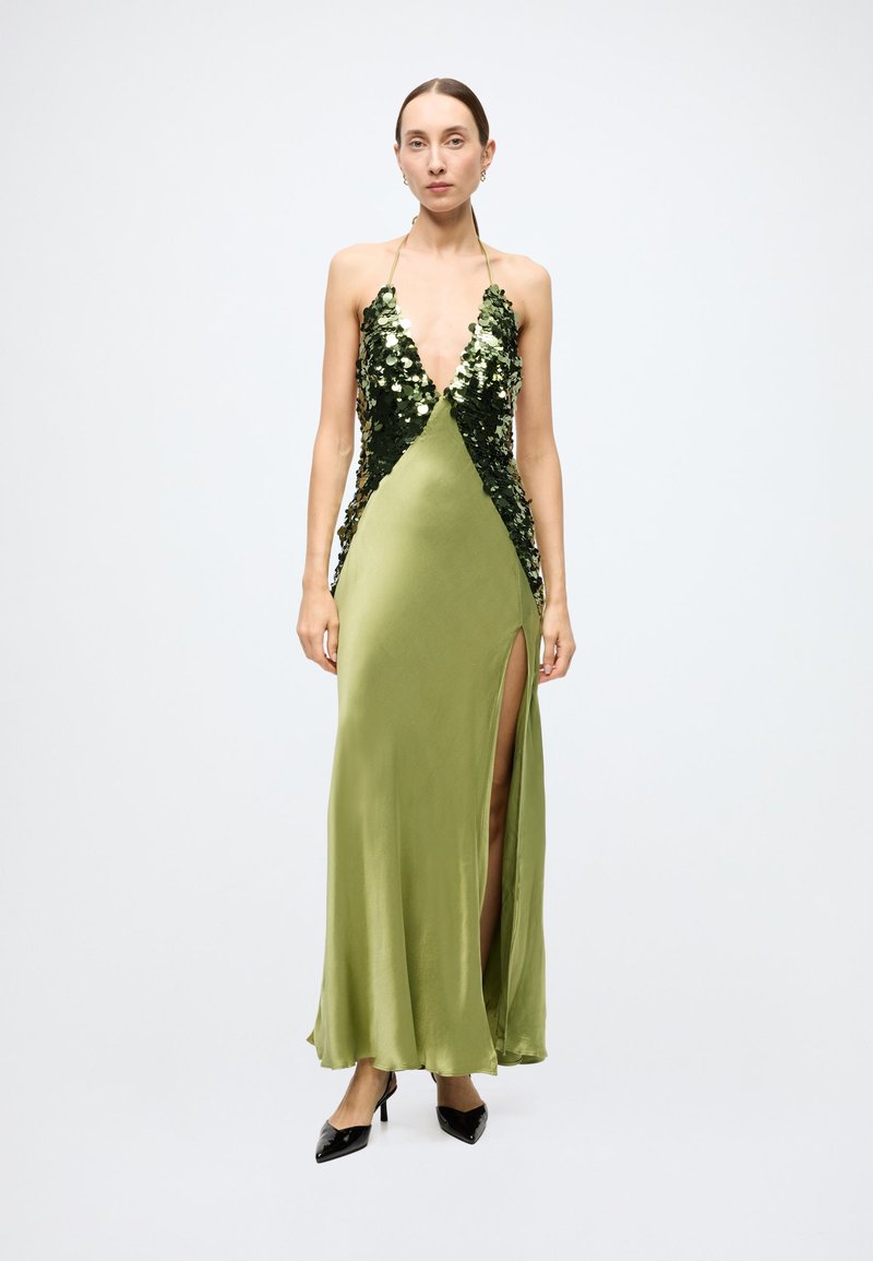 Halter-neck evening gown in olive green satin, featuring sequin detailing on the bodice and a thigh-high slit on one side. Black heels.
