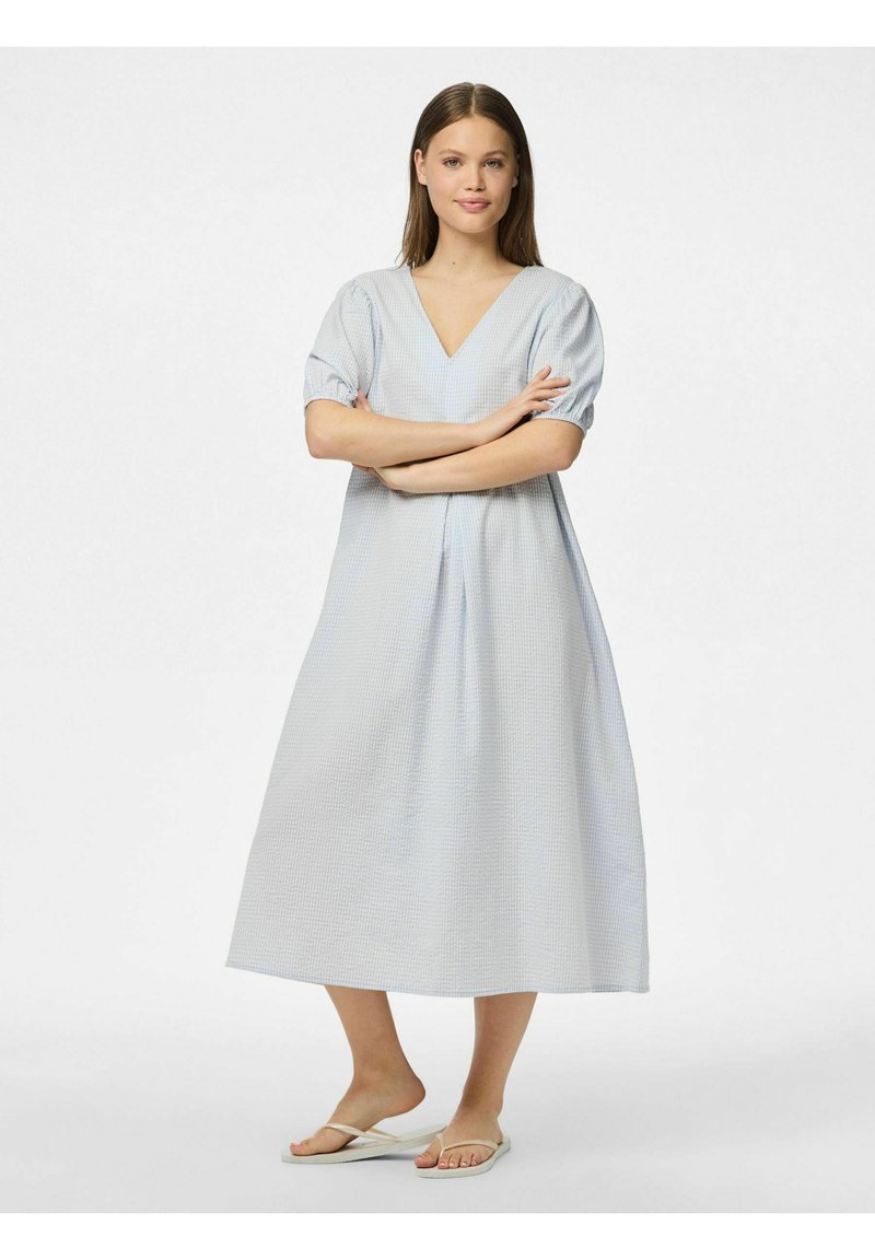 Ljusblå midi-klänning med V-ringning, korta puffärmar, ett strukturerat tygmönster och en avslappnad passform, kombinerad med vita flip-flops.