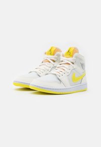 Pair of white high-top Nike Air sneakers with yellow soles, yellow swoosh logos, and yellow accents on tongue and collar.