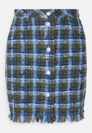 Karierte Rock aus strukturiertem Stoff in Blau, Grün und Weiß mit Fransenbesatz und sechs lila Knöpfen auf der Vorderseite.