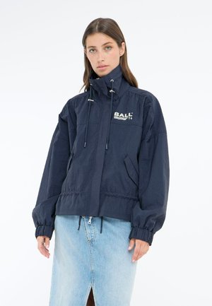 Navy blue jacket features a high neck, elastic cuffs, drawstring hem, and logo detail. Material appears lightweight with a smooth texture.