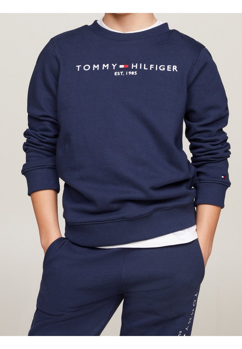 Granatowy sweter z okrągłym dekoltem, ściągaczami przy rękawach i u dołu. Z przodu haft "TOMMY HILFIGER EST. 1985". Miękka struktura tkaniny.