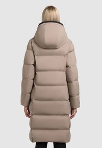 Gestepptes, knielanges beiges Parka mit Kapuze, das horizontale, gesteppte Abschnitte, eine glatte Textur und einen schwarz gefütterten Kragen aufweist.