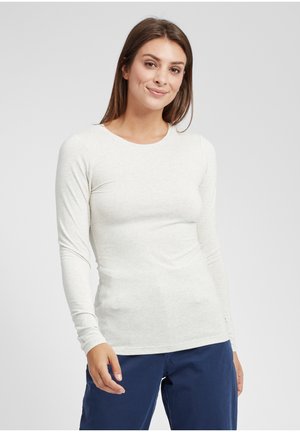 Ljusgrå långärmad topp i ett mjukt, stretchigt material med rund halsringning och figurnära siluett, tillsammans med mörkblå byxor.