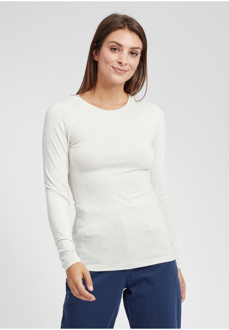 Ljusgrå långärmad topp i ett mjukt, stretchigt material med rund halsringning och figurnära siluett, tillsammans med mörkblå byxor.