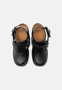 Ζευγάρι μαύρα δερμάτινα clogs με λουριά στον αστράγαλο και ασημένιες αγκράφες, με ταμπά εσωτερικές σόλες με την επωνυμία "TOGA PULLA".