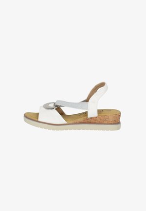 White wedge sandal with a cork heel, featuring a silver circular accent and a soft grey elastic strap. Smooth leather and textured insole.