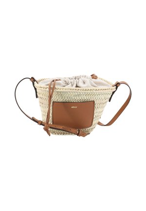 Woven straw crossbody bag with tan leather front pocket, adjustable strap, and beige fabric drawstring closure at the top.