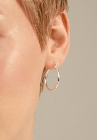 Silver hoop earring with a polished finish, featuring a small stud detail above. Simple circular design, worn on the lobe.