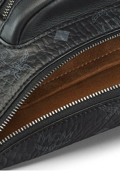 Borsa in pelle nera con superficie testurizzata, dotata di zip argento, fodera marrone e dettaglio del logo. L'interno rivela una texture simile alla pelle scamosciata.