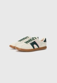 Sneakers with a cream canvas upper, green laces, green and pink side accents, and a brown rubber sole. Rounded toe design.