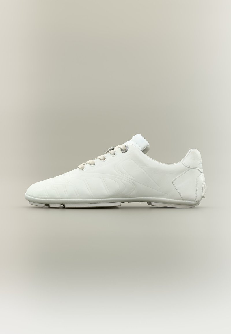 Chaussure de sport blanche profil bas avec lacets, design épuré et semelle lisse et minimaliste sur fond neutre.