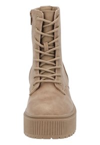 Botas de tobillo beige con cordones, de textura suave, punta redonda y suela de goma gruesa con estrías verticales; detalle de cremallera lateral.