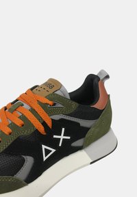 Mnohofarebné tenisky s hornou časťou zo zelenej semišovej látky a čiernej sieťoviny, oranžové šnúrky, sivé akcenty a biele geometrické logo na boku.