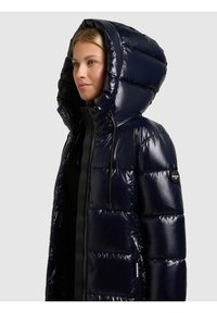 Tumši zila pūkaina jaka ar spīdīgu apdari, tai ir liela kapuce, rāvējslēdzēja aizdare un sānu kabatas. Teksturēts sižetēts dizains ar logotipa akcentu.