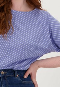 Korte mouwen blouse, licht paars met witte strepen, met een diagonale naadontwerp en een relaxte fit, gecombineerd met denim jeans.