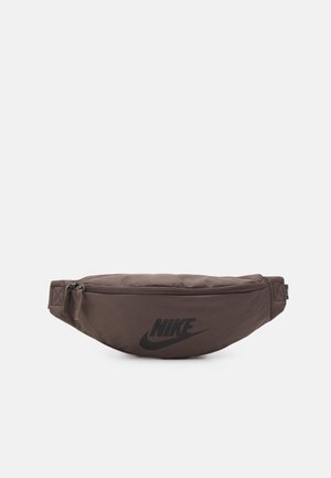 Sac banane Nike marron avec logo noir et poche zippée, conçu pour un transport mains libres.