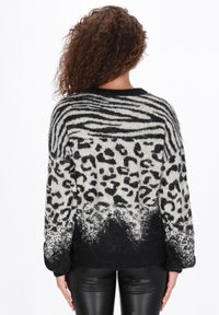 Trui met een zwart en crème dierenprint met zebrapatronen en luipaardvlekken, textuurstof en een zwarte ribbelzoom.