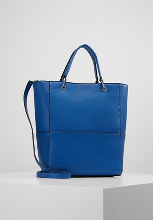 Niebieska skórzana torba typu tote z podwójnymi uchwytami i regulowanym paskiem na ramię, prezentowana na białym postumencie na szarym tle.