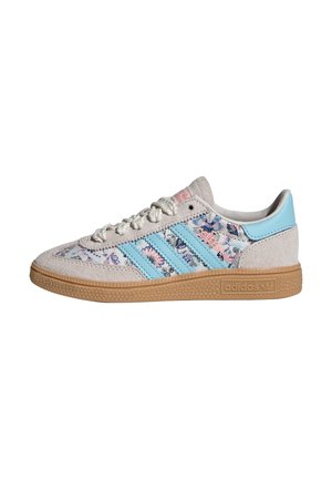 Baskets basses Adidas en daim beige, avec des rayures bleues, un motif floral sur les côtés en tissu, une semelle en gomme et une fermeture à lacets.