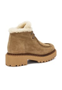 Botas de tobillo de ante marrón con un cuello de pelo sintético color crema, puntera redonda y suela de goma gruesa con un patrón de tracción. Diseño bajo con cordones.