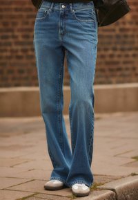 Lysblå denim flared jeans med høj talje, der har frontlommer og kontrastsyninger. Blød tekstur og en let falmet finish.