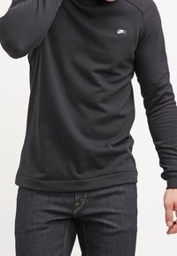 Svart långärmad sweatshirt i ett mjukt material, med rund halsringning, ribbade muddarna och en liten Nike-logotyp på bröstet.