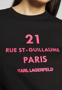 Czarna koszulka z krótkim rękawem z wyrazistym różowym napisem: "21 RUE ST-GUILLAUME PARIS" oraz "KARL LAGERFELD", z okrągłym dekoltem.
