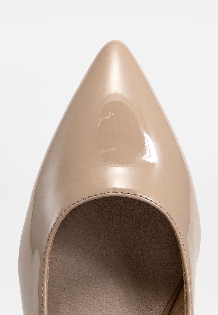 Chaussure pour femme à talon aigu en beige brillant avec un dessus en cuir lisse et des coutures visibles autour de l'ouverture, photographiée de dessus.