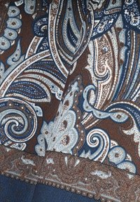 Tkanina z wzorem paisley w odcieniach brązu, niebieskiego i kremowego. Złożony wzór zawiera spirale, motywy kwiatowe i szczegółowe akcenty.