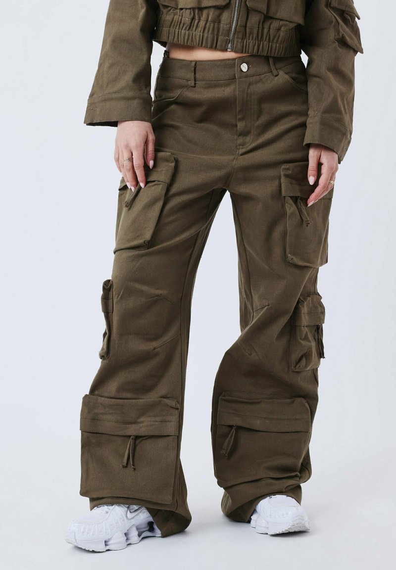Pantalons cargo vert olive avec de multiples poches, poignets ajustables et coupe décontractée, fabriqués en tissu léger. Pantalons à l'avant plat avec fermeture à bouton.