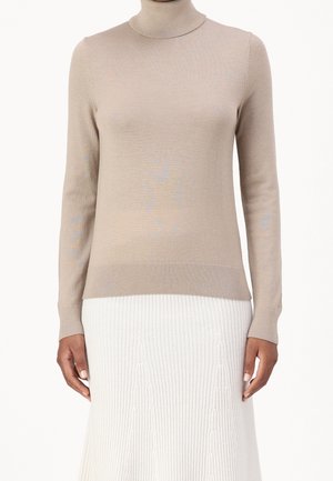 Pull à col montant beige en tricot côtes, doté de manches longues et d'une coupe ajustée. Le tissu semble doux avec un éclat subtil.