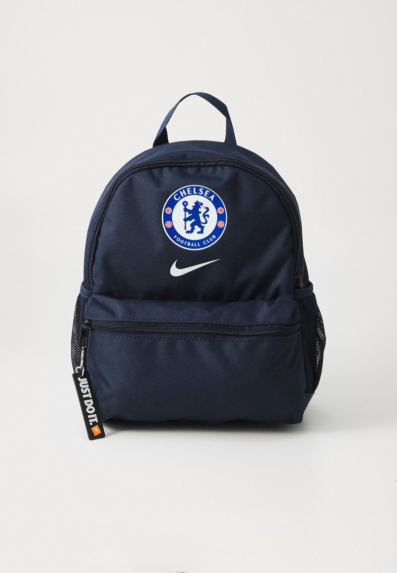 Mørkeblå ryggsekk laget av slitesterkt stoff, med et sirkulært Chelsea Football Club-logo og en hvit Nike-swoosh. Side-nettinglommer inkludert.