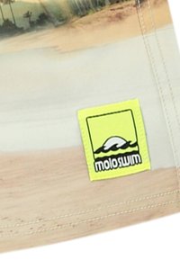 Gaišu krāsu peldbikses ar pludmales ainavas rakstu, kurām ir spilgti dzeltena birka ar "moloswim" logotipu.