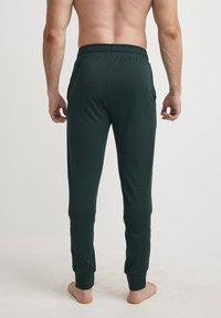 Donkergroene, lichtgewicht joggingsbroek van zachte stof, met een elastische tailleband en aansluitende boorden bij de enkels.