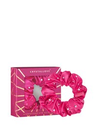 Różowa jedwabna gumka do włosów z kryształowymi akcentami, wyeksponowana w różowym pudełku w geometryczny wzór. Wyraźny połysk i miękka faktura.