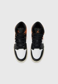 Svart og hvitt høyhælte sneakers med oransje detaljer, med perforert tåboks og teksturert materiale, snøret og sett fra oven.