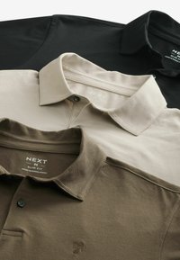 Drei Poloshirts übereinander gestapelt: schwarz, beige und olivgrün. Jede hat einen Kragen und eine Knopfleiste mit sichtbaren Logoetiketten.