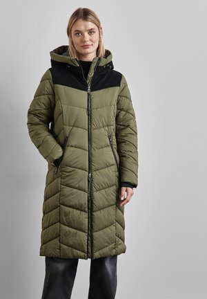 Manteau long rembourré vert olive avec un panneau noir. Présente une fermeture éclair, deux poches latérales et une capuche, avec une texture matelassée.