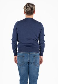 Maglione blu navy lavorato a maglia con maniche lunghe, vestibilità slim, polsini a coste, abbinato a jeans in denim blu medio con tasche posteriori e gamba dritta.