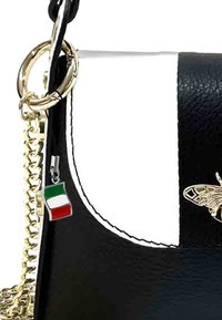 Sac en cuir noir et blanc avec une bandoulière en chaîne dorée, arborant un emblème de papillon et un charme représentant le drapeau italien.