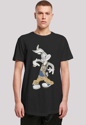 Black t-shirt featuring Bugs Bunny graphic, wearing a blue shirt and beige pants, with white sneakers and gold chain accents.