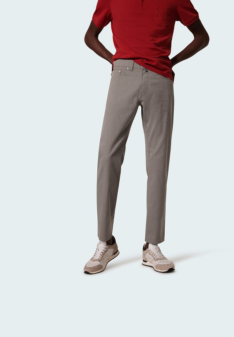 Gray checkered trousers with a fitted design, paired with a red polo shirt and beige sneakers with textured accents.