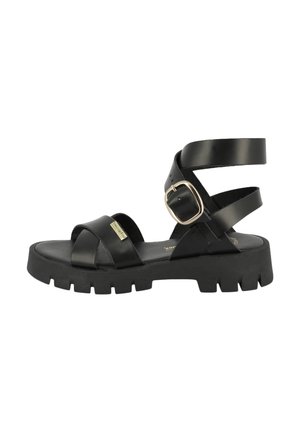 Black sandals feature a chunky sole, crossed straps at the front, and a wide ankle strap with a gold buckle detail.