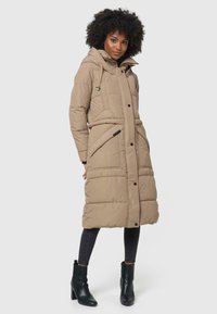 Beige gewatteerde jas met een capuchon, voorzien van een rits aan de voorkant, drukknoopsluiting en zijzakken. Draagbaar over donkere jeans en zwarte enkellaarsjes.