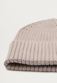 Knit beanie in light beige with ribbed texture and a folded cuff. Features a soft fabric with even stitching and neat edges.