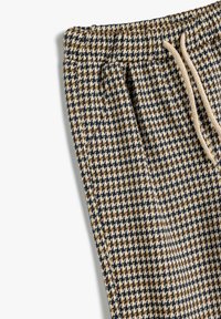 Rutig bukser i beige, brun og marineblå med elastisk talje og snor. Har et tekstureret stof med et hundetandmønster.