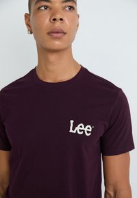 Bourgogne kortærmet t-shirt lavet af bomuld, med et lille hvidt "Lee" logo på venstre brystområde. Glat tekstur, klassisk pasform.